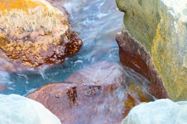 dalgalar ve fışkıran deniz su akan büyük taşların üzerinde