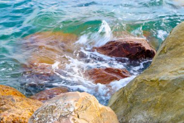 dalgalar ve fışkıran deniz su akan büyük taşların üzerinde
