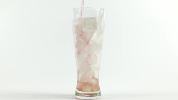 氷の立方体で満たされたガラスにジュースを注ぐ — ストック動画