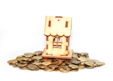 İpotek kredisinin sembolü olarak altın paraların üzerindeki ahşap ev