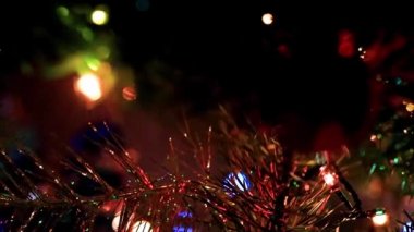 Noel ağacının dallarında şenlikli aydınlatma ve cam oyuncaklar