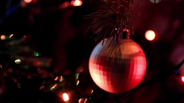 クリスマスツリーの枝にお祝いのイルミネーションとガラスのおもちゃ — ストック動画