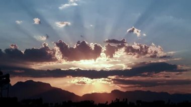 Kentsel binaların çatıları üzerinde bulutlu bir gökyüzünde güzel güneş ışınları