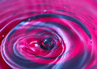 bir damla su, çok renkli bir sıvının yüzeyine düşer