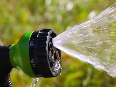 çim nemlendirilmesi için bir sprey nozul ile sulama hortumu