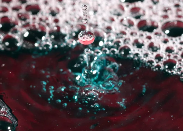 Een Druppel Water Valt Het Oppervlak Van Een Multi Gekleurde — Stockfoto