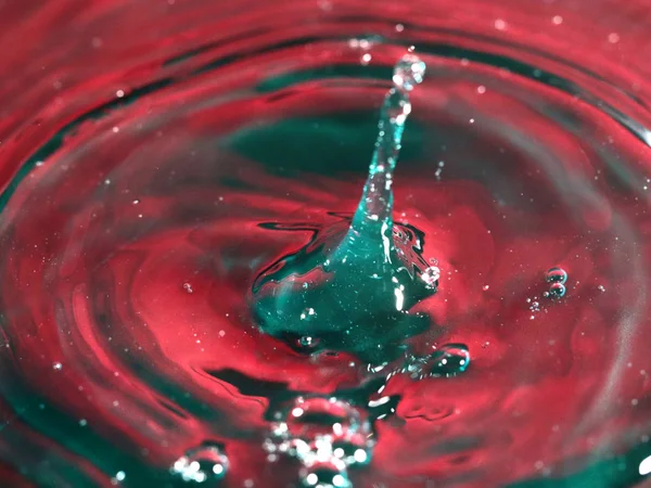 a drop of water falls on the surface of a multi-colored liquid