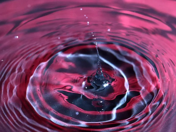 a drop of water falls on the surface of a multi-colored liquid
