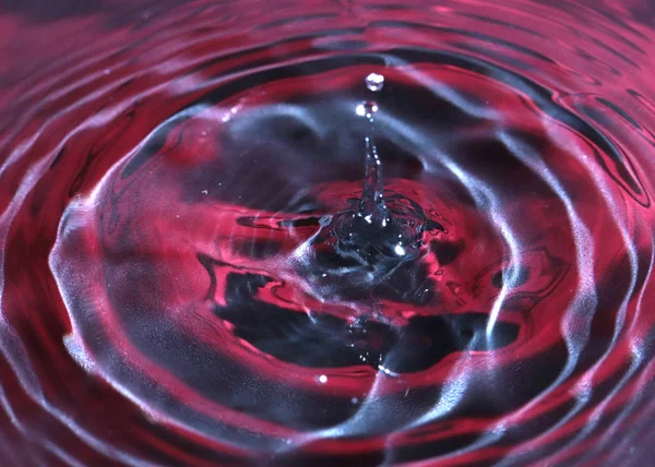 a drop of water falls on the surface of a multi-colored liquid