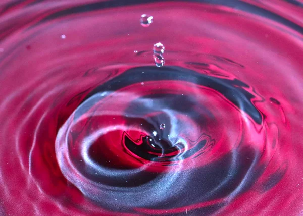 a drop of water falls on the surface of a multi-colored liquid