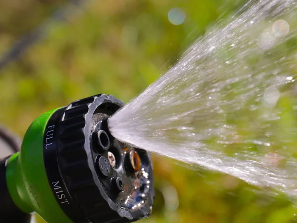 watering hose with a spray nozzle for moistening the lawn