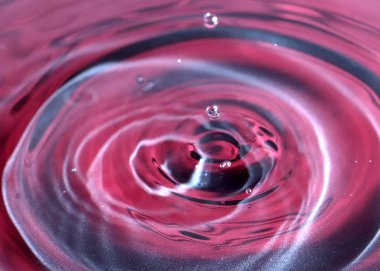 kırmızı sıvının yüzeyine bir damla su düşer