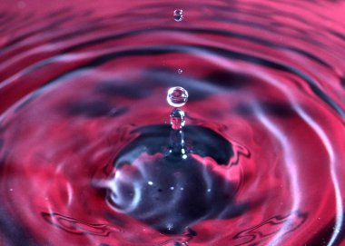 kırmızı sıvının yüzeyine bir damla su düşer