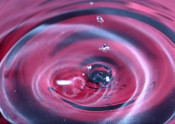 kırmızı sıvının yüzeyine bir damla su düşer