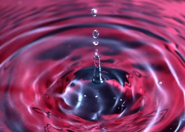 kırmızı sıvının yüzeyine bir damla su düşer