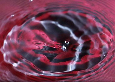 kırmızı sıvının yüzeyine bir damla su düşer