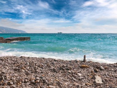 plajda kendi taşpiramidi ve güneşli bir gökyüzü altında berrak deniz suyu