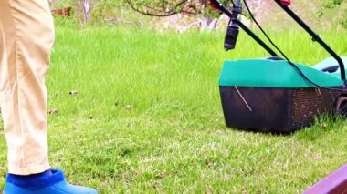 Çim biçme makinesiyle çimlerin çimlerini biçiyorum.