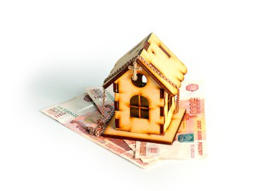 wooden house on banknotes Russian ruble and a gold chain with a cross as a symbol of protection of savings