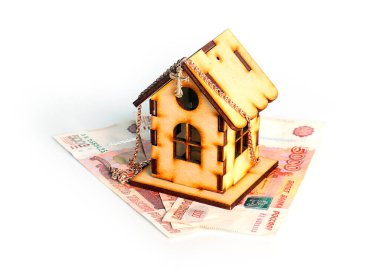 wooden house on banknotes Russian ruble and a gold chain with a cross as a symbol of protection of savings