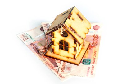wooden house on banknotes Russian ruble and a gold chain with a cross as a symbol of protection of savings