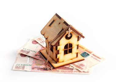 wooden house on banknotes Russian ruble and a gold chain with a cross as a symbol of protection of savings