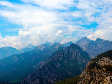 Dağların tepeleri güneşli bulutlu bir gökyüzüne karşı