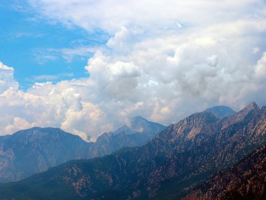 Dağların tepeleri güneşli bulutlu bir gökyüzüne karşı