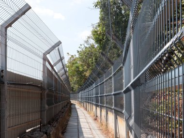 Korunaklı bir alanda metal çit ve yaya geçidi.