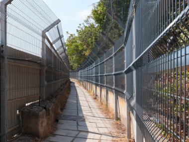 Korunaklı bir alanda metal çit ve yaya geçidi.