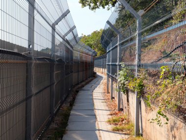 Korunaklı bir alanda metal çit ve yaya geçidi.