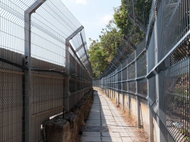Korunaklı bir alanda metal çit ve yaya geçidi.