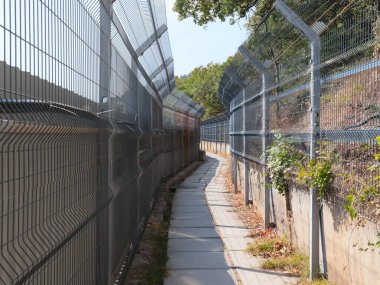 Korunaklı bir alanda metal çit ve yaya geçidi.