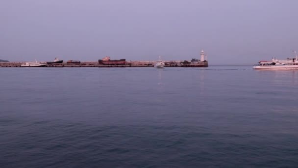 商船の動きと港の水域の桟橋のちらつき灯台 — ストック動画