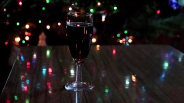 Bir kadeh kırmızı şarap ve yılbaşı ağacı aydınlanması.