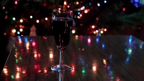 赤ワインのグラスとクリスマスツリーの新年のイルミネーション — ストック動画