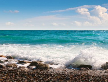 Ufukta deniz plajı ve güneşli gökyüzü.