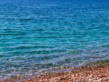 Çakıl taşlı deniz sahilinde küçük dalgalar kopar