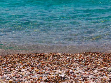 Çakıl taşlı deniz sahilinde küçük dalgalar kopar