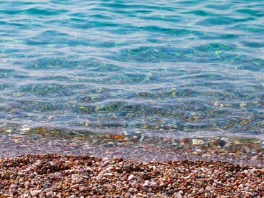 Çakıl taşlı deniz sahilinde küçük dalgalar kopar