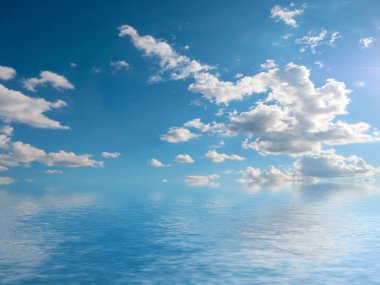 Deniz yüzeyinde bulutlu, güneşli bir gökyüzünün yansıması.