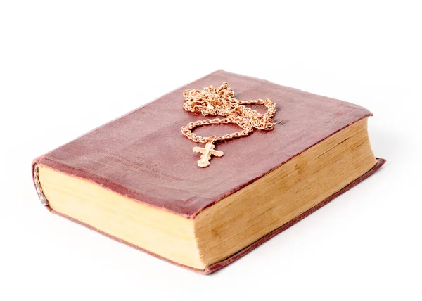 一条带有基督教十字架的金项链被放在一本旧书上 — 图库照片