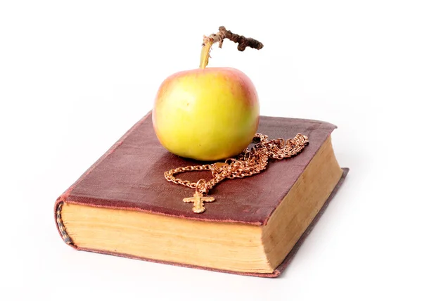 熟したリンゴの横に十字のついたキリスト教の古い本と金の鎖 — ストック写真