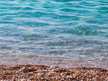 Küçük dalgalar ve denizin kumlu plajı.