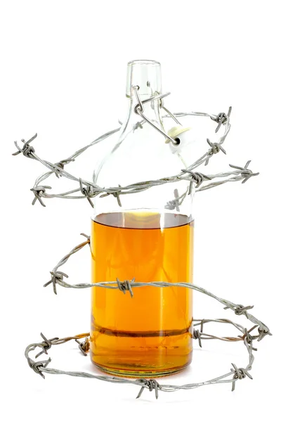 Barbed wire around a glass bottle of alcohol — Stock Photo, Image