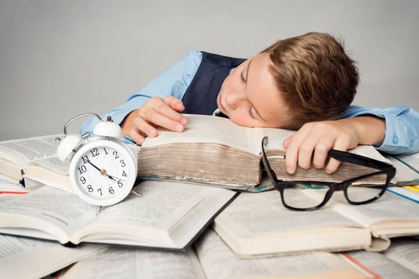 孩子睡在书本上 疲惫的学生孩子学习 脸上躺在书本上闹钟旁 孩子们刻苦教育的理念 — 图库照片