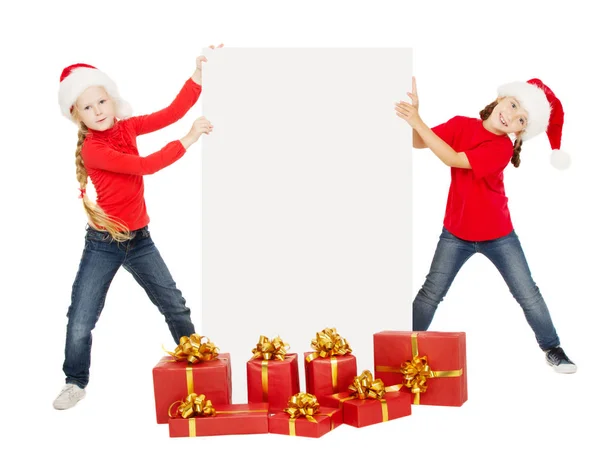 圣诞节孩子与广告牌横幅超过白色 孩子在红帽持有空白海报卡与现有礼品盒在孤立的背景 — 图库照片