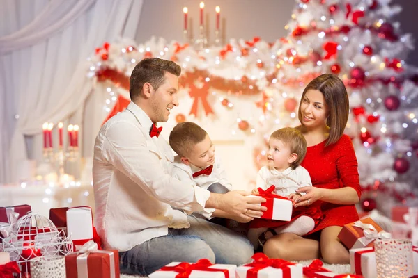 クリスマス家族プレゼント ギフトのオープン フロント クリスマス ツリー 幸せなお父さんお母さんの子供と赤ちゃん — ストック写真