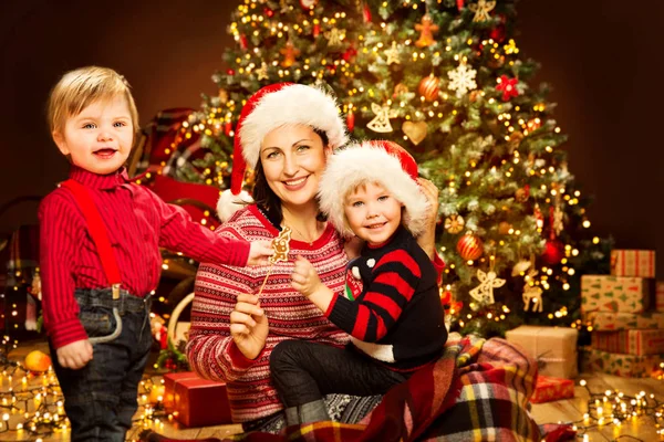 圣诞节家庭 母亲与孩子在圣诞树灯前面 快乐的妈妈和婴儿在红帽 — 图库照片