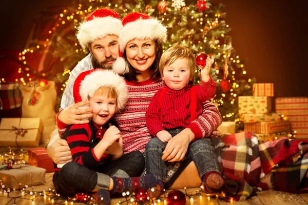 圣诞树 快乐的母亲孩子和婴儿在毛衣和红帽的圣诞节家庭前面 — 图库照片